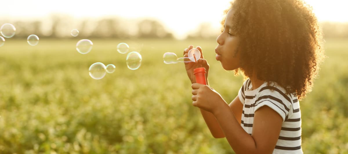 Young Black girl blowing bubbles while playing